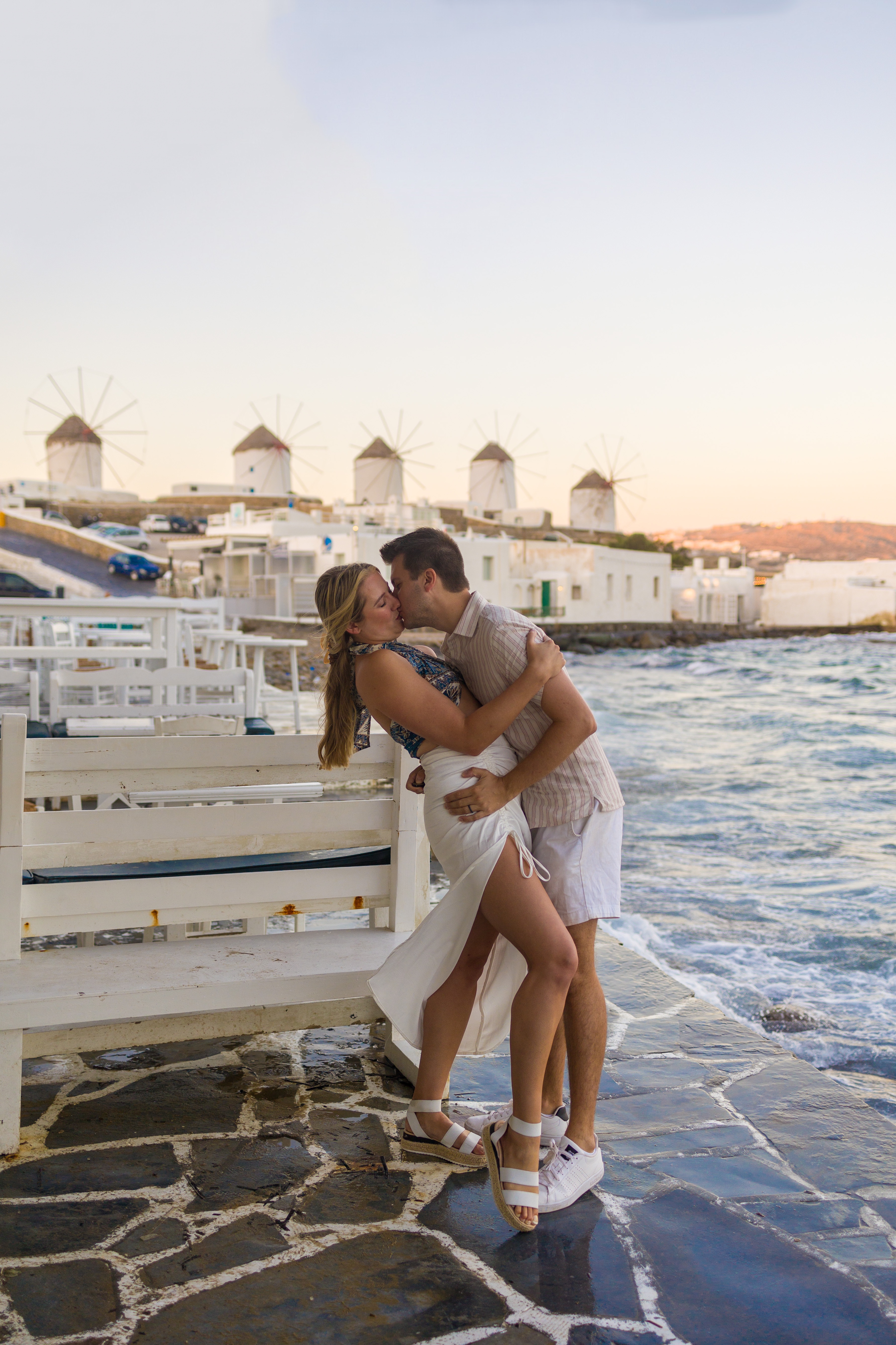 Couple kissing in Little Venice outside five windmills in Mykonos
